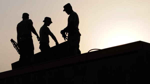 Silhouetted workers on a roof