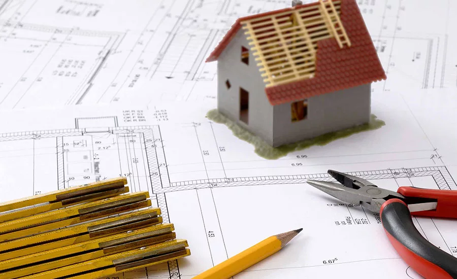 BLueprints and a model house with an incomplete roof.