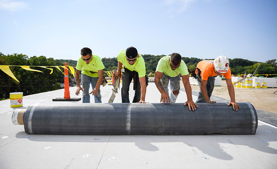 Four men working on a commercial roofing project