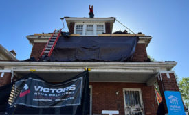 A roofer from Victor’s Home Solutions stands on a roof the company is replacing in coordination with Habitat for Humanity..