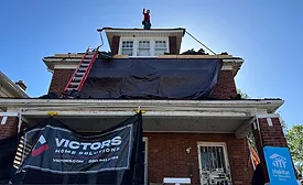 A roofer from Victor’s Home Solutions stands on a roof the company is replacing in coordination with Habitat for Humanity..
