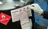 OSHA-Labeling A hazardous materials label being placed onto a drum (pictured).