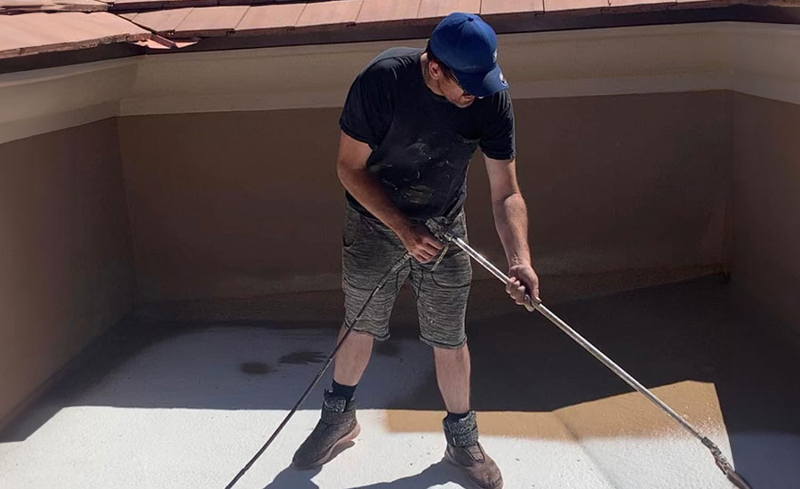 A man applying spray foam on a flat roof