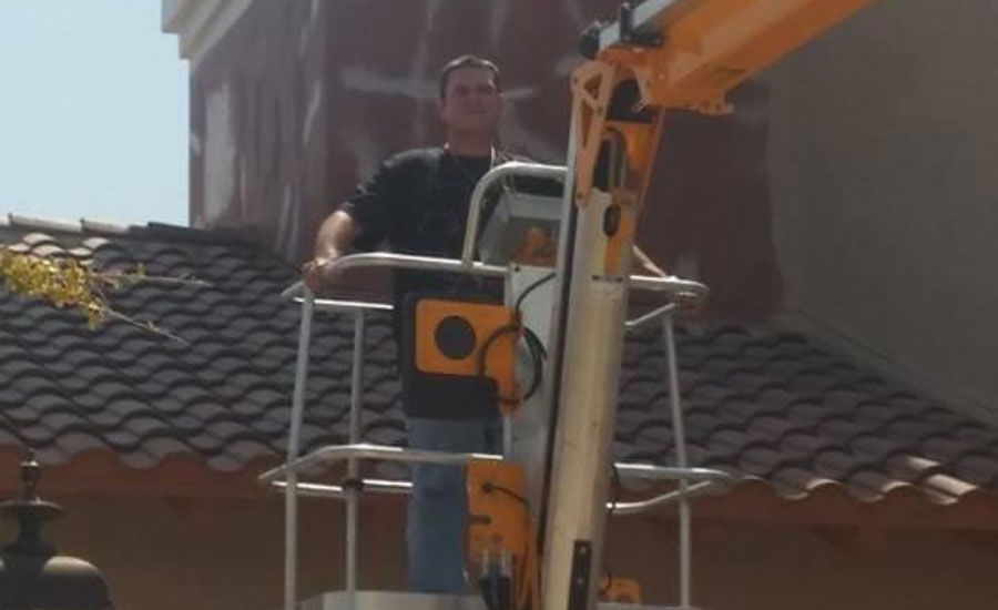 A man on a lift in front of a church roof