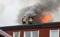 roof-fire.jpg 2 firefighters on top of a burning building