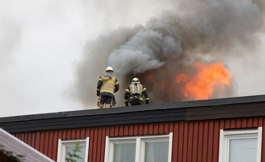 2 firefighters on top of a burning building
