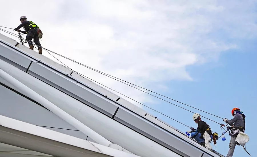 roofers rappelling on a sloped commercial roof