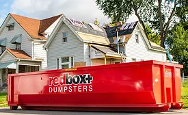 redbox-roofing-dumpster-in-front-of-half-roofed-home