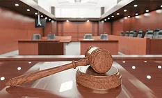A gavel resting on the judge's bench in a coutroom