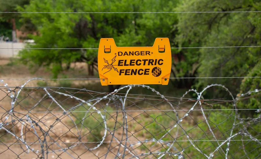 yellow-electric-fence-sign-on-barbed-wire-in-forest-area
