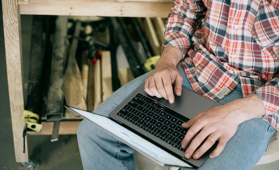 man-wearing-flanne-and-jeans-in-workshop-on-computer
