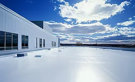 A white commercial roof under a blue sky on a partly cloudy day