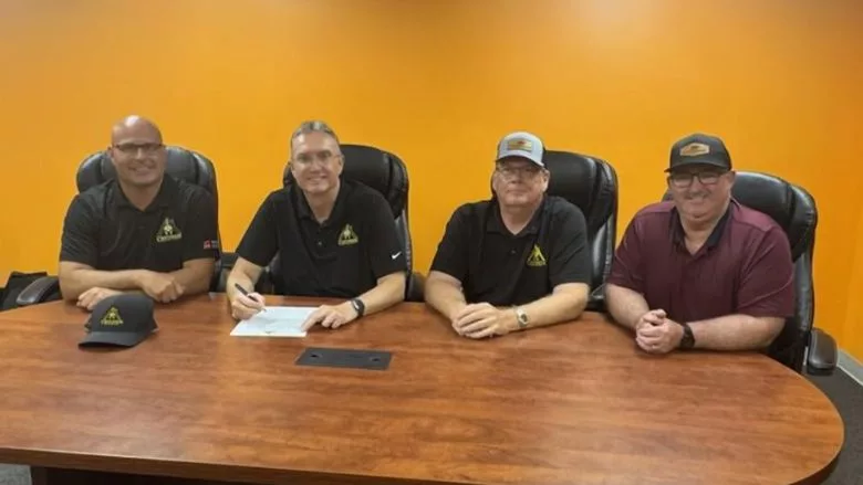 The teams at a table for the contract signing