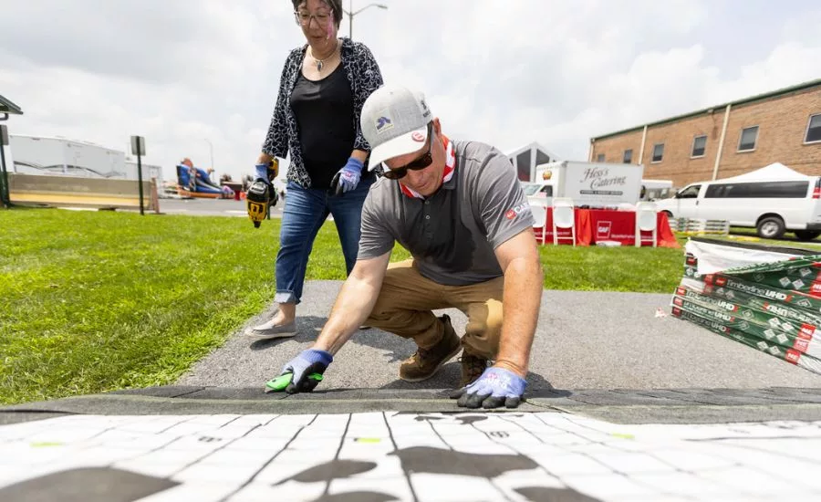 Two GAF employees participate in shingle event outdoors