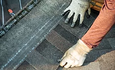 Hands placing shingles on a roof