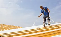 A man applying a roof coating