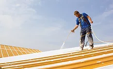 A man applying a roof coating