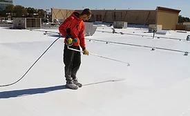A man applying a roof coating
