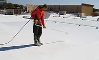 A man applying a roof coating