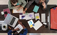 A meeting table with graphs, charts, laptops, and coffee