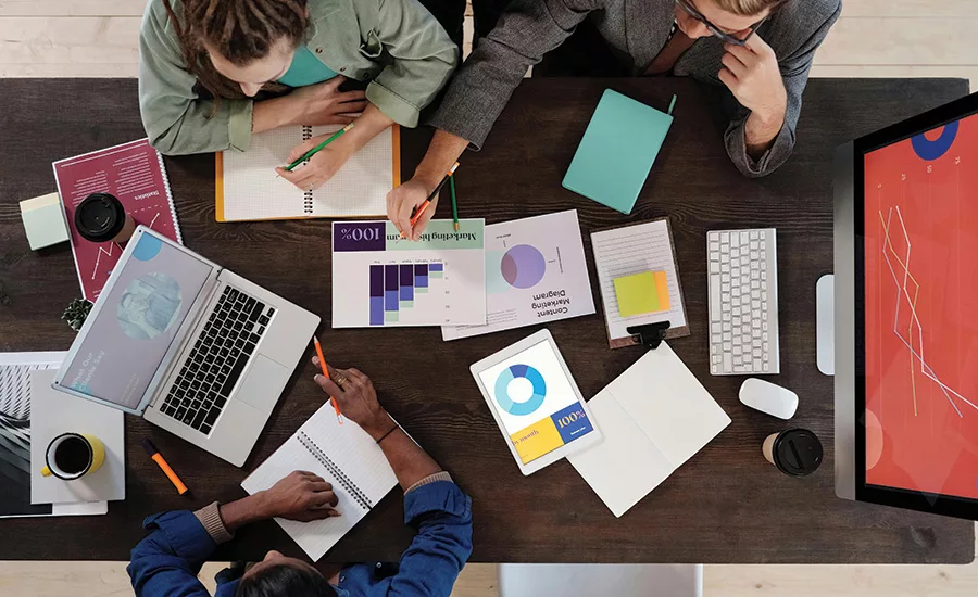 A meeting table with graphs, charts, laptops, and coffee