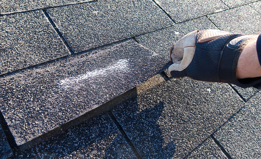 Residential roof inspection for an insurance claim due to storm damage. The asphalt shingles show signs of damage.