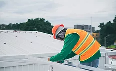 worker-measuring-on-metal-roof worker-in-safety-gear-on-metal-roof