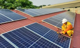 man-wearing-safety-gear-installing-solar-panels-on-roof