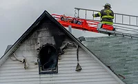 firefighter-on-ladder-truck-inspecting-burned-building
