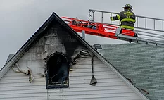 firefighter-on-ladder-truck-inspecting-burned-building