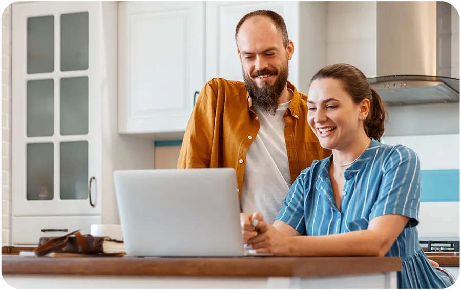 smiling-young-married-couple-talking-via-video-call-using-laptop-at-home-in-kitchen-interior