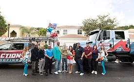 team stands alongside Action Roofing trucks