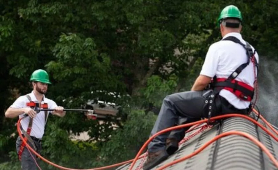 two contractora applying roof rejuvenation product to a residential roof