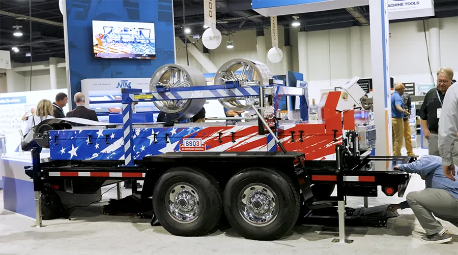 An American flag-painted SSQ3 trailer-mounted machine at a trade show, with people around it.