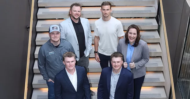 Six young roofing professionals standing on stairs