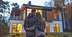 A couple stands facing a very nice home