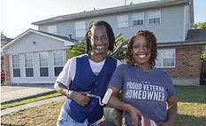 Homeowners stand beside their house with a newly installed roof after hurricane repairs improved storm protection. Homeowners stand beside their house with a newly installed roof after hurricane repairs improved storm protection.