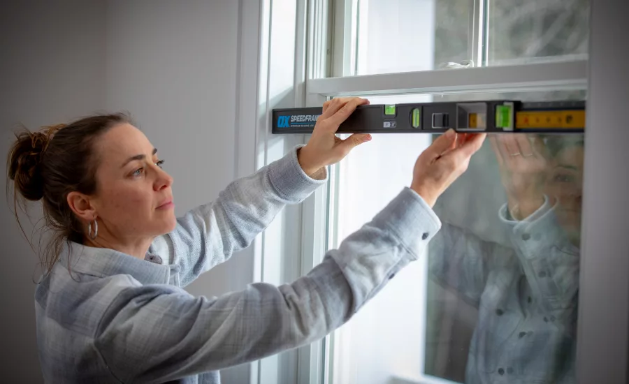 Woman using the OX Pro SPEEDFRAME on a window. 