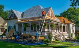 roofers replace shingles on a home