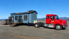 red semi truck hauling a tiny home
